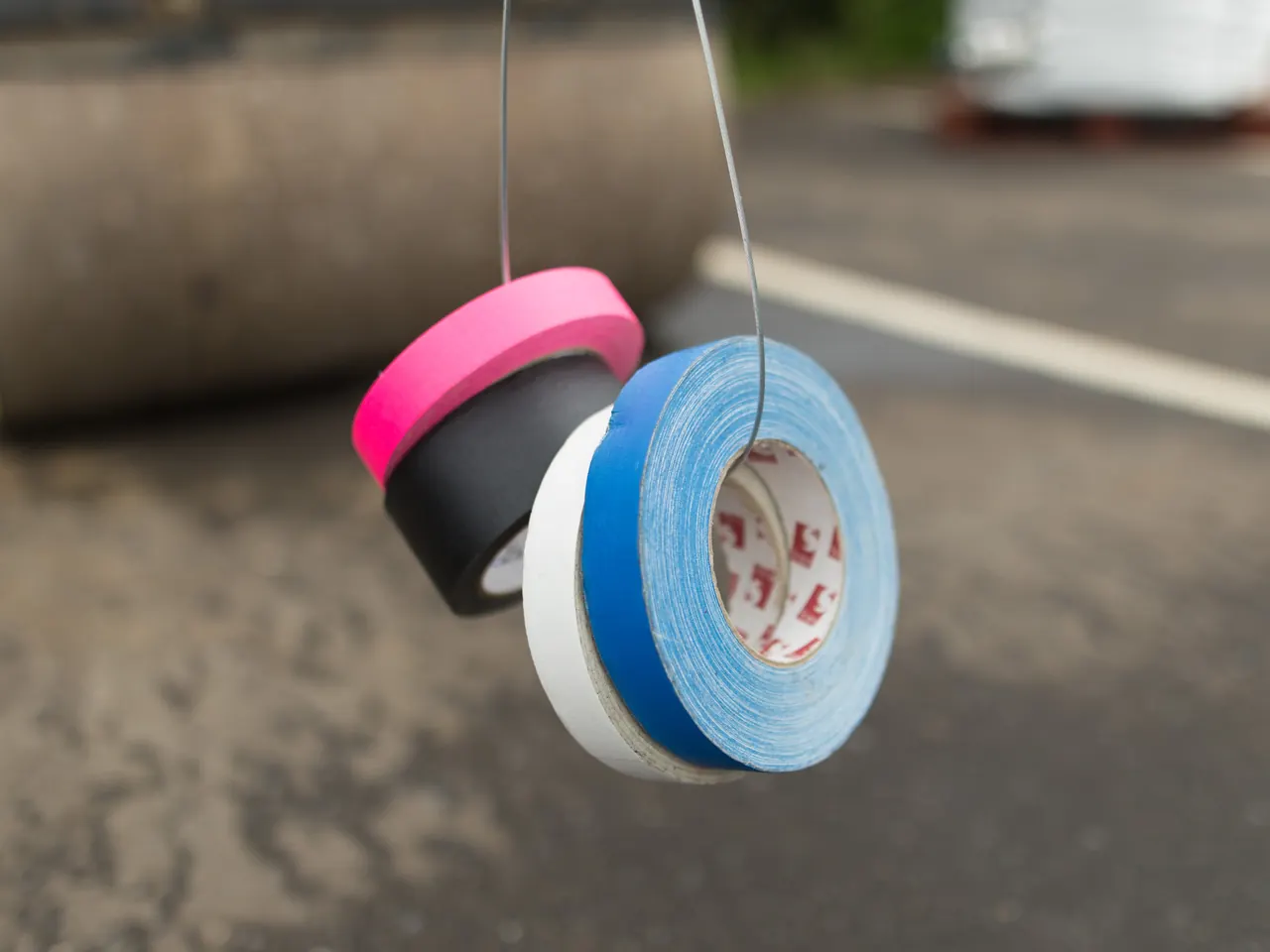 Rolls of pink, black, white and blue gaffer tape hanging from a wire